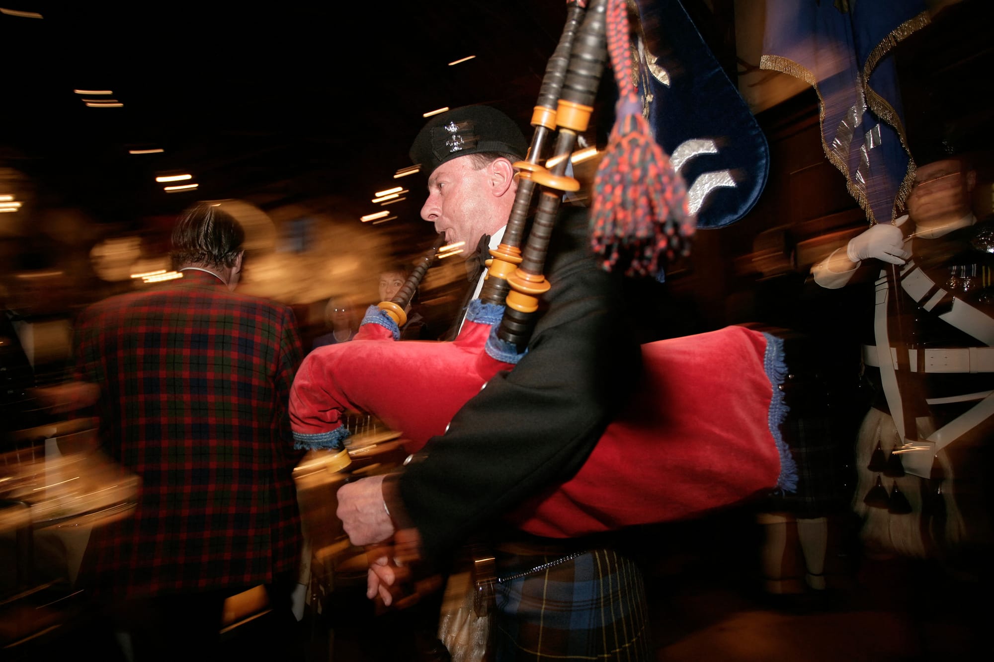 A piper in full kilt regalia enters a Burns Supper.