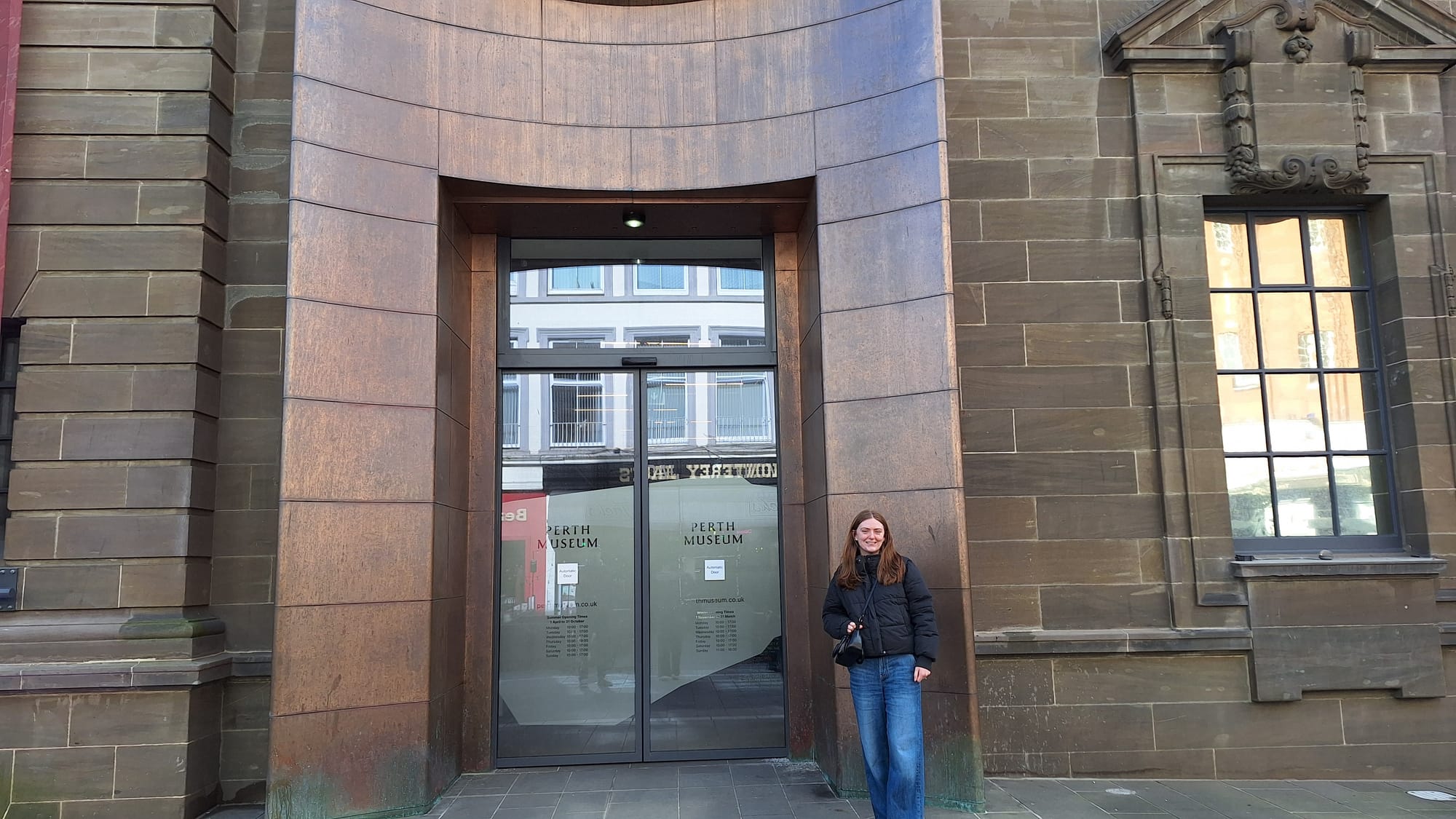Beth wears a black puffy jacket outside the new Perth Museum.