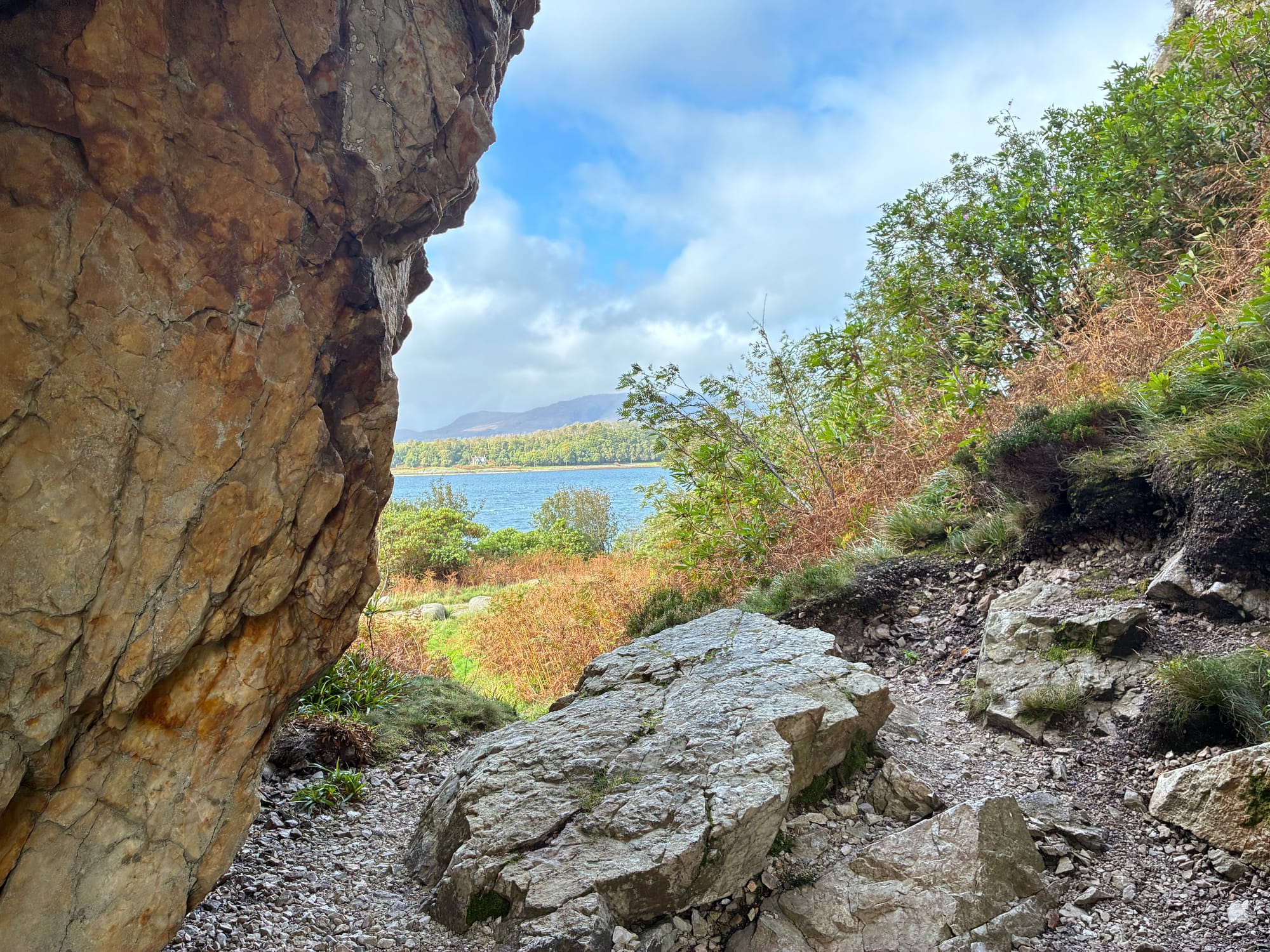the view through the rock arch looks to bright blue sea and a green island.