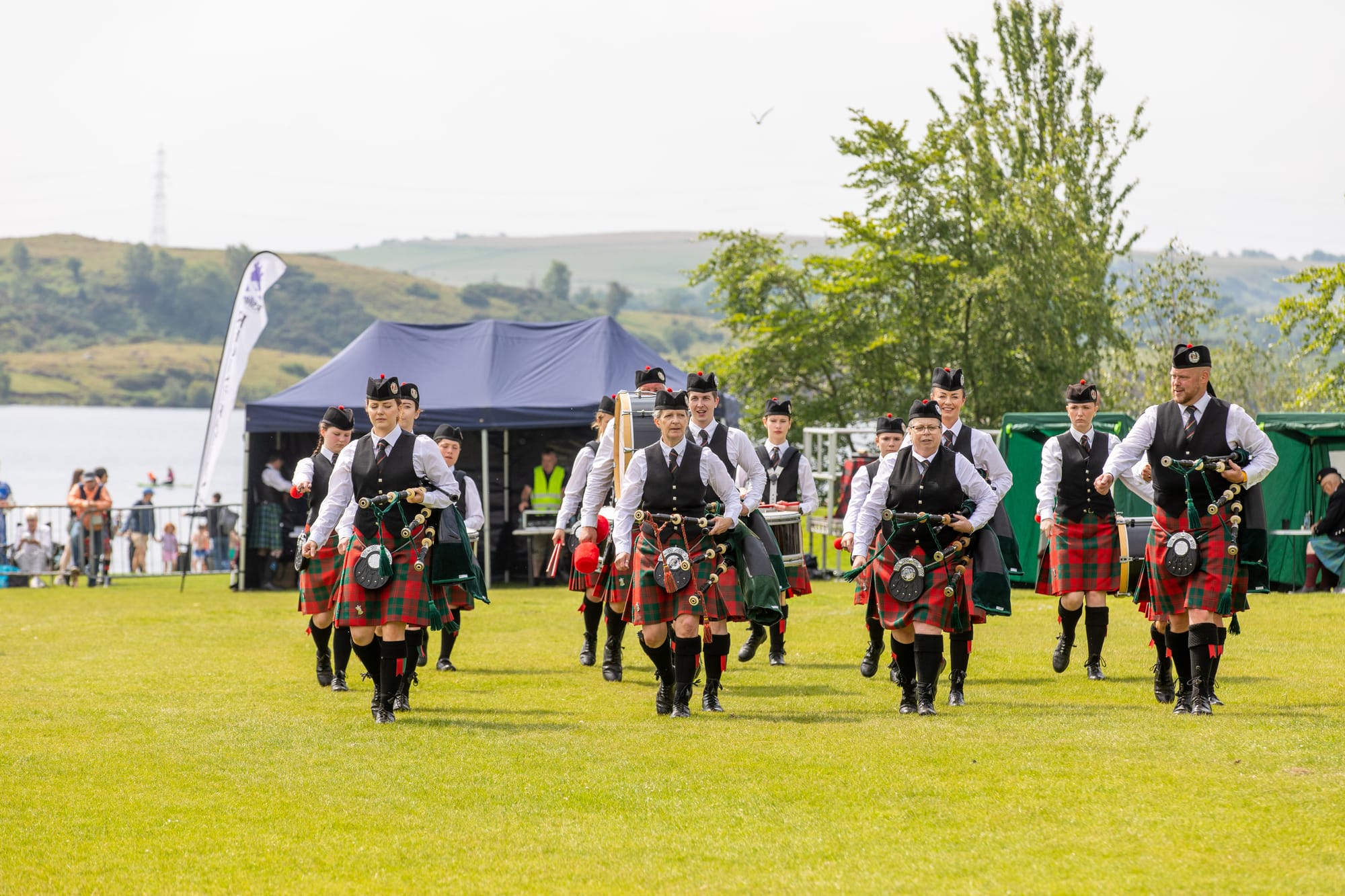 A contemporary photo from Highland Games showing a mixed-gender pipe band.