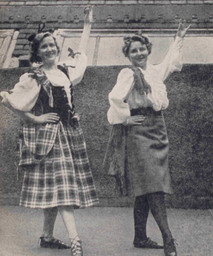 A black-and-white photo of two women wearing long skirts and white blouses.