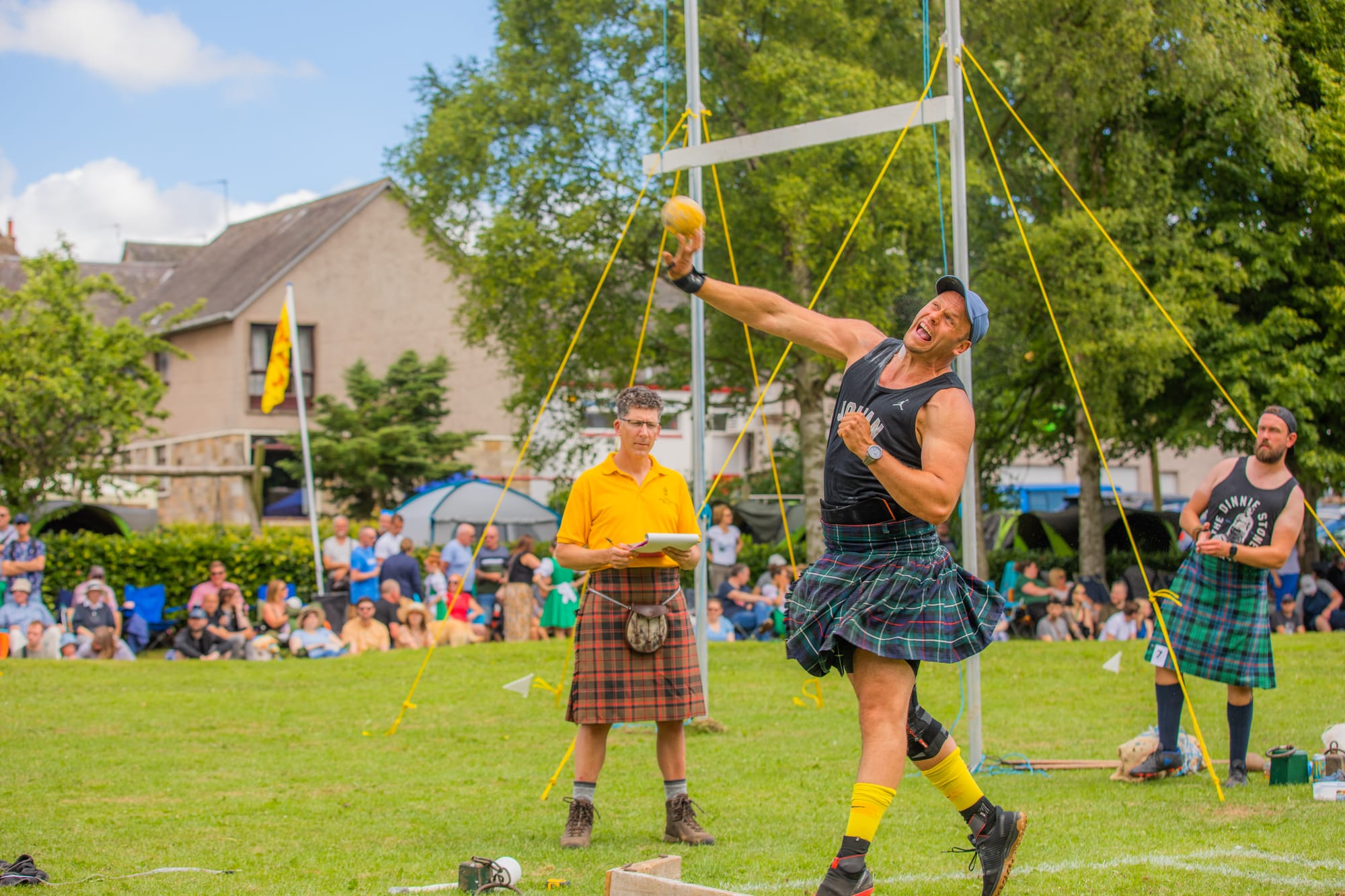 A scene from Ceres Highland Games, showing a man in a kilt participating in shot putt.