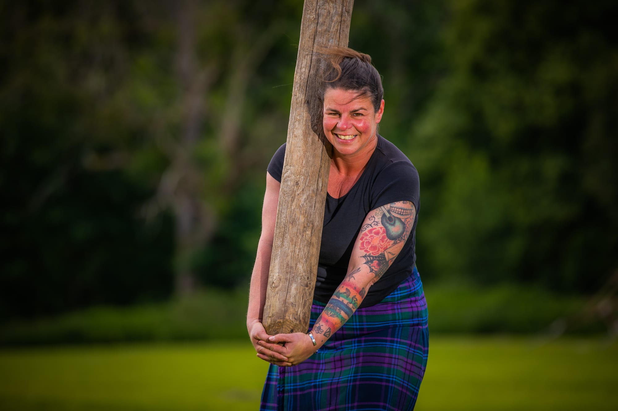 Rebecca wearing a kilt and holding a caber upright with her hands.