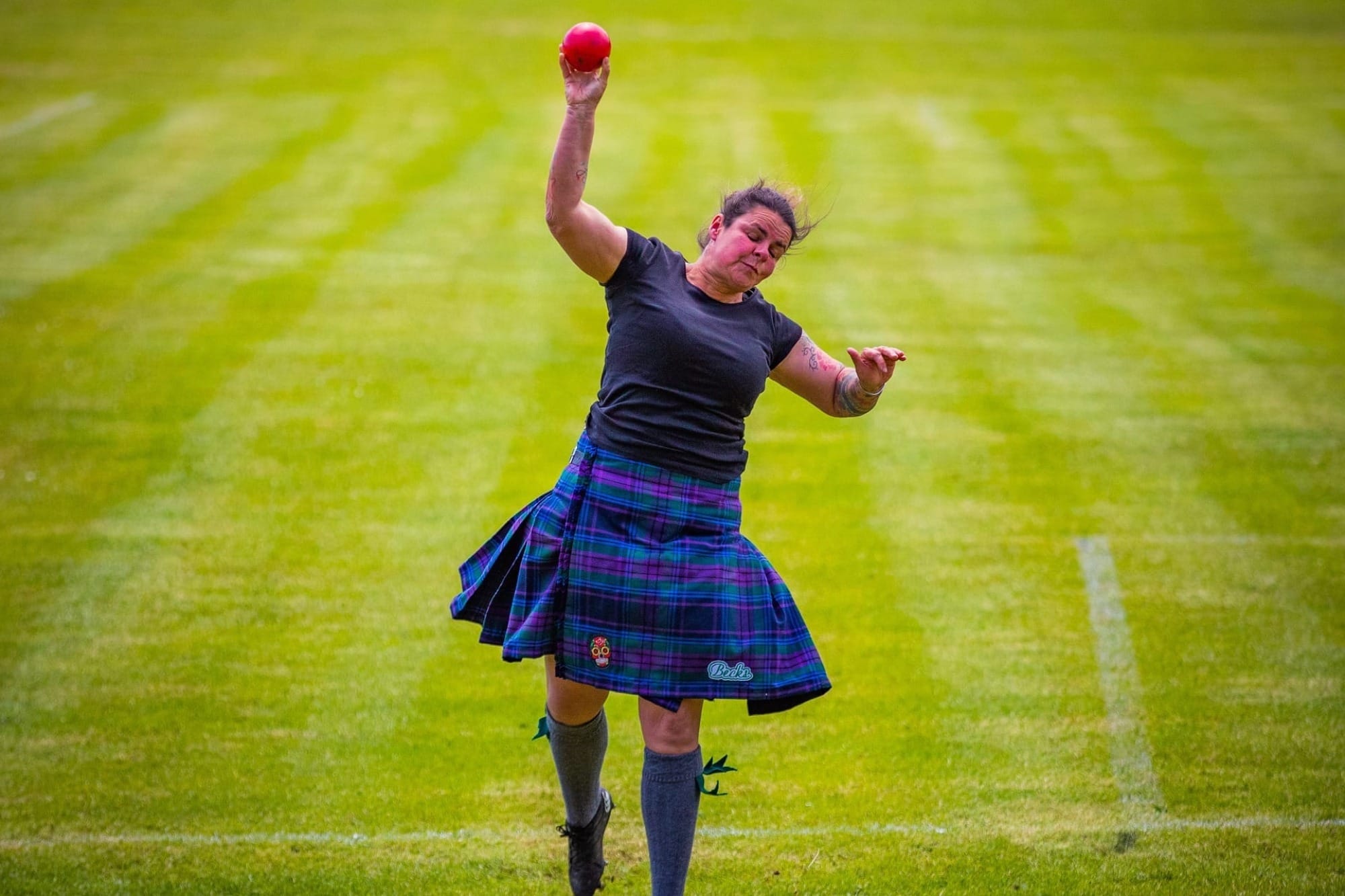 Rebecca throwing a shot put while wearing a kilt.