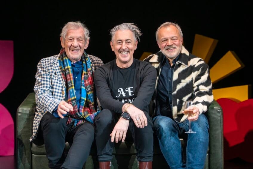 Ian McKellen, Alan Cumming and Graham Norton together on a sofa.