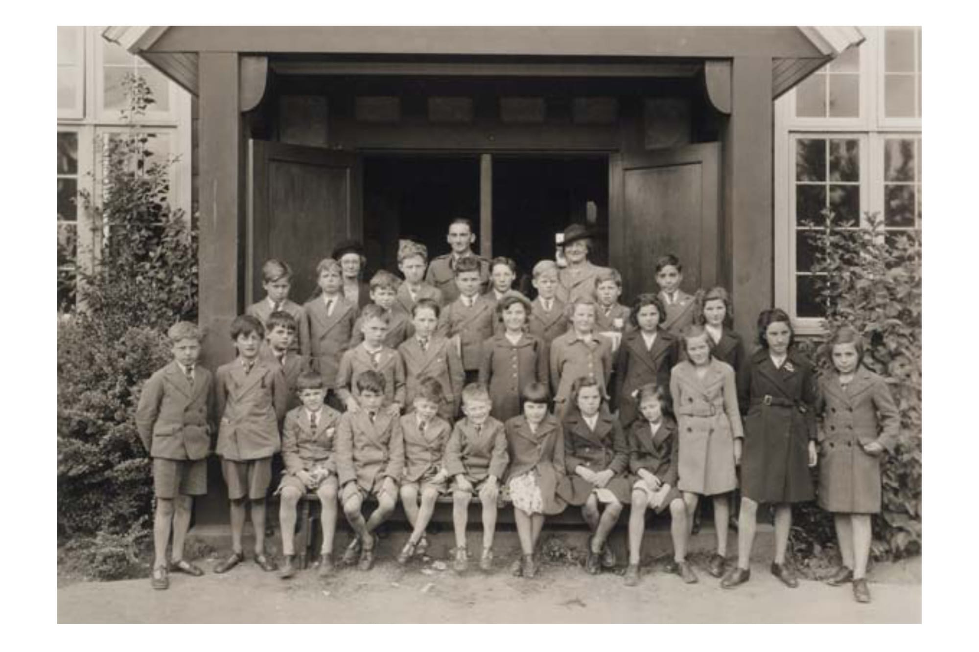 A black and white photo of school children in a large doorway.
