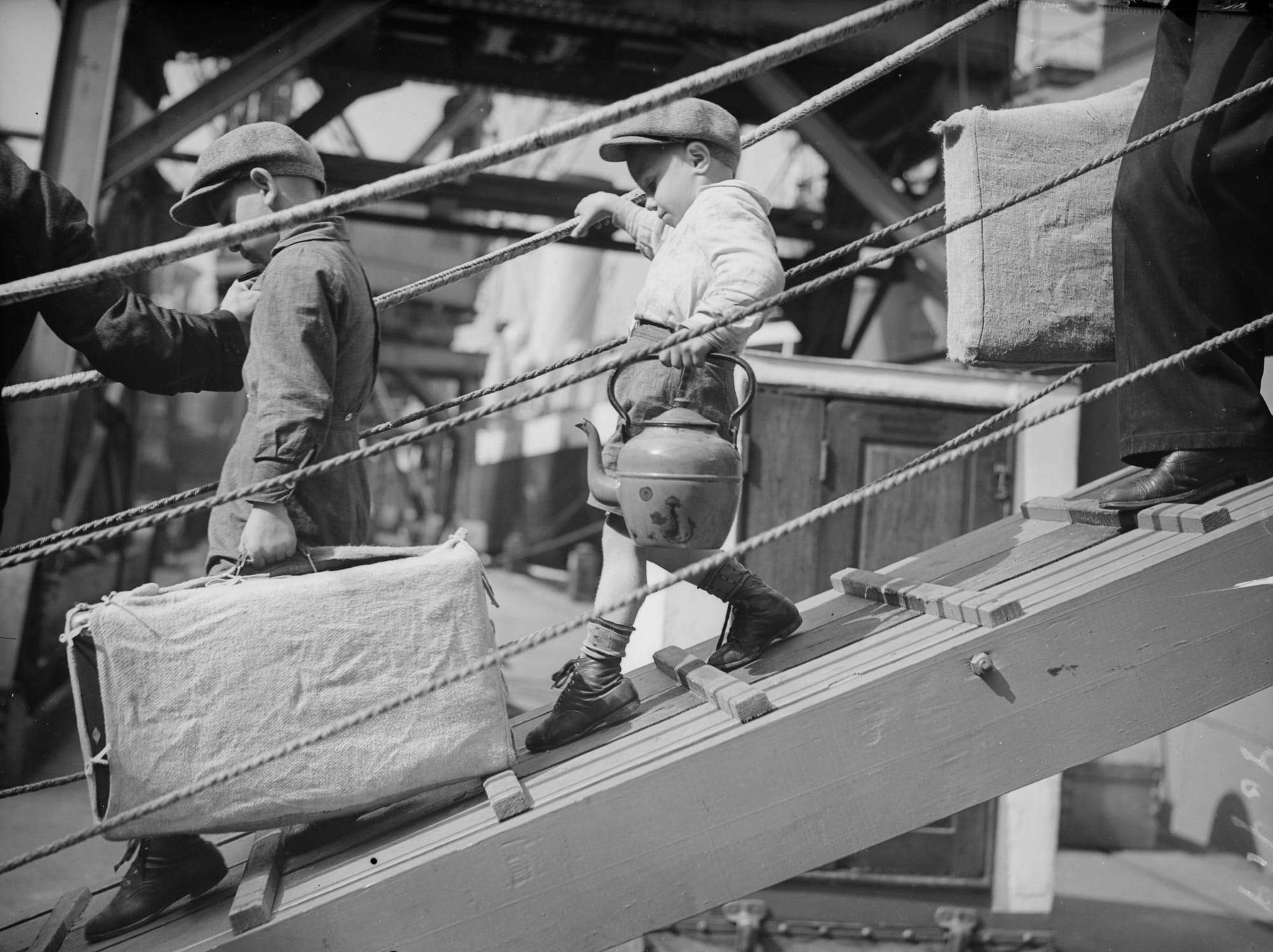 A black and white photo of young children boarding a ship.