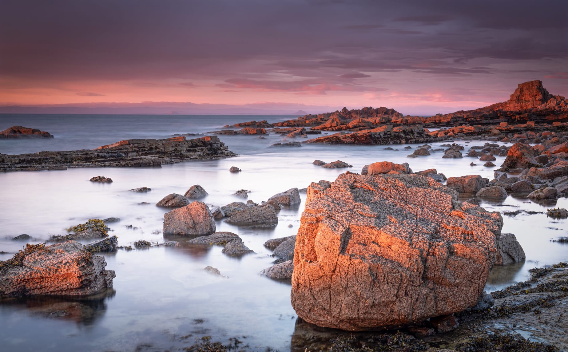 Large boulders next to the coast at sunset.