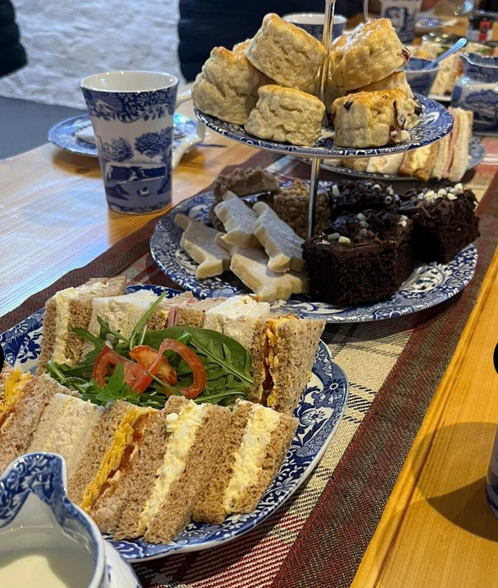 An afternoon tea with sandwiches, scones, shortbread and cakes on a table at Kitchen Coos and Ewes