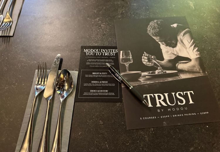 Cutlery lying on a napkin next to the Trust menu.