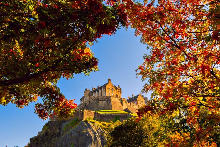 EdEdinburgh Castle framed by autumn leaves in a picture taken from below at one of the city's parks.