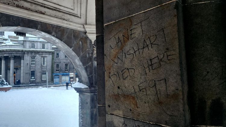Graffiti written beneath a monument in Aberdeen that says 'Jane Wishart Died Here In 1597'.