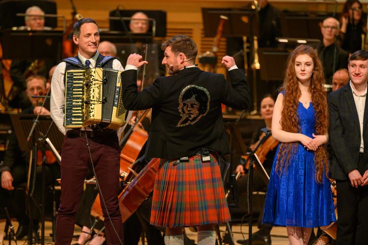 Ally Heather with his back to the audience on the BBC's Burns Night programme pointing to a sequined image of Burns on the back of his jacket.