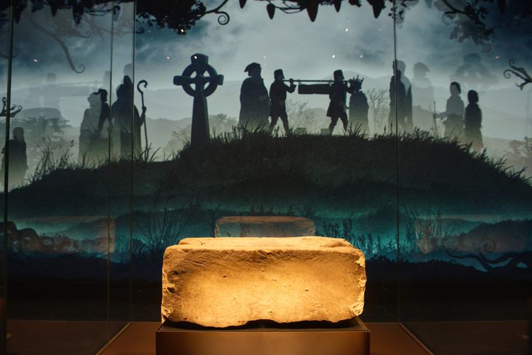 The Stone of Destiny on display in a glass cabinet. There is an illustration of a coronation projected on the wall at the back.