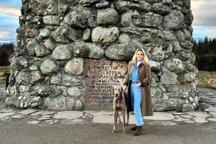 Emily and her dog standing by a large stone memorial cairn at the battlefield.