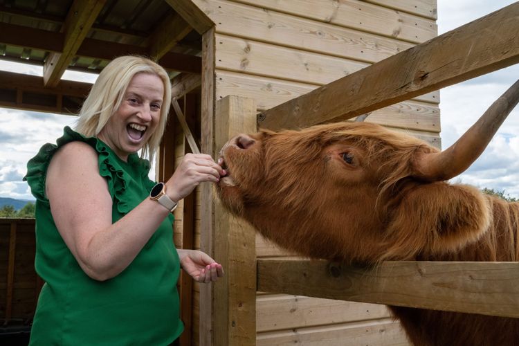 Debbie Clarke smiles as she hand-feeds Corrie, a red Highland cow, during the Highland cow experience at Crieff Hydro in Perthshire.