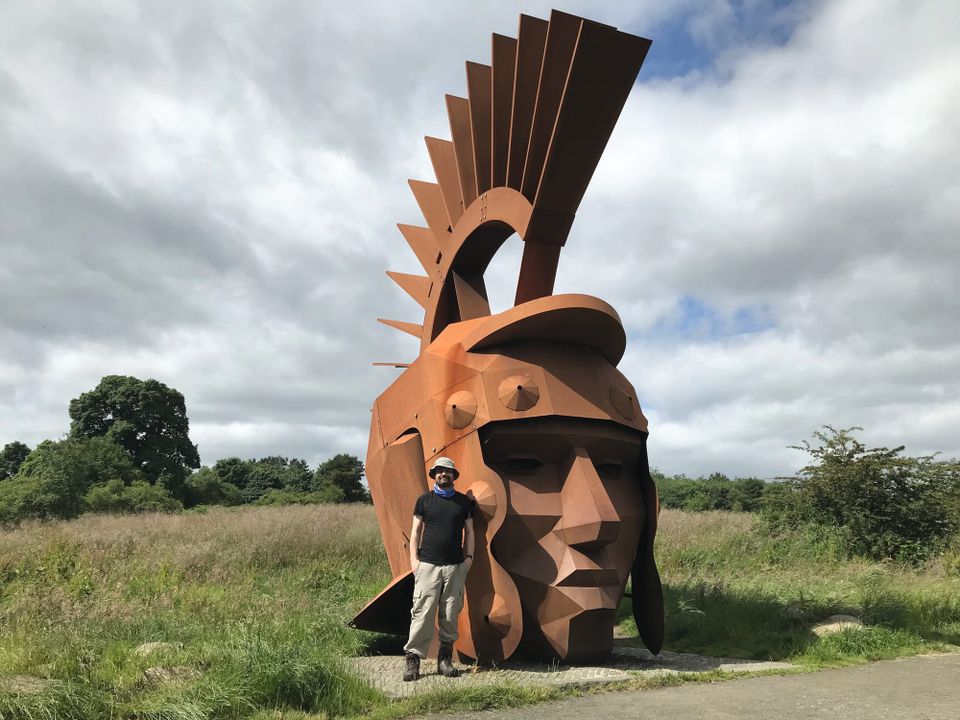 Peter next to a large brown sculpture of the head of a Roman centurion.