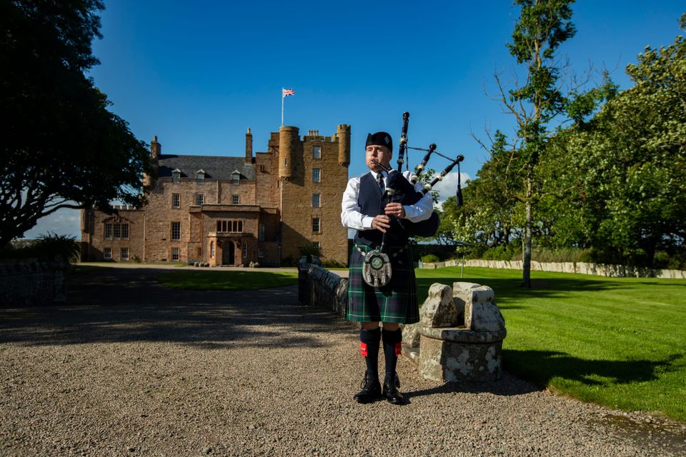A piper in a kilt outside the Castle of Mey.