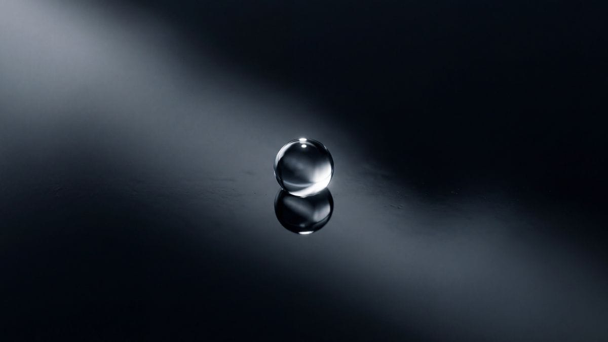 A pristine drop of water on smooth black obsidian, representing ultimate mental clarity and a dopamine reset.