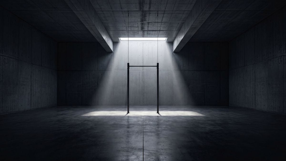 A minimalist, empty training space with a single pull-up bar illuminated by a shaft of light.