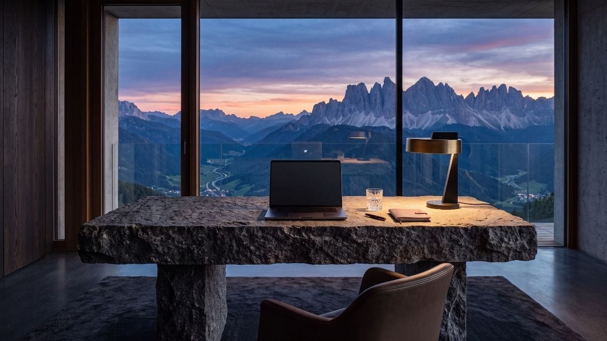 A luxury minimalist workspace with a laptop overlooking a mountain range, representing focus and building a global community.