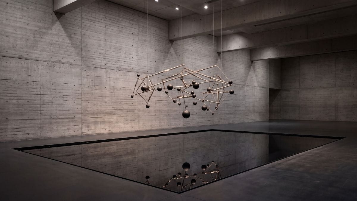 Precision titanium sculpture suspended over a dark reflecting pool, symbolizing proximate cause and causation.