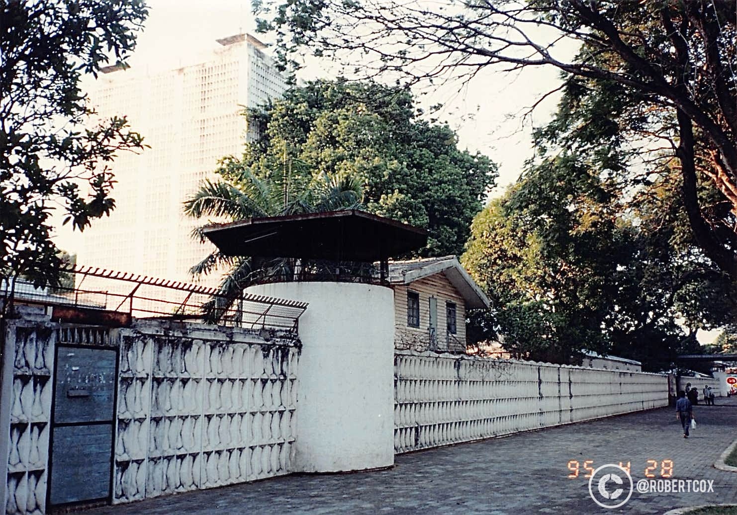 The exterior of the former U.S. Embassy in Saigon. The distinctive wall with its geometric pattern and the gate match historical images of the embassy compound. The embassy building itself was demolished in the late 1990s, but in 1995, it was still standing, though no longer in use as an embassy after the U.S. withdrawal in 1975. (April 29, 1995)