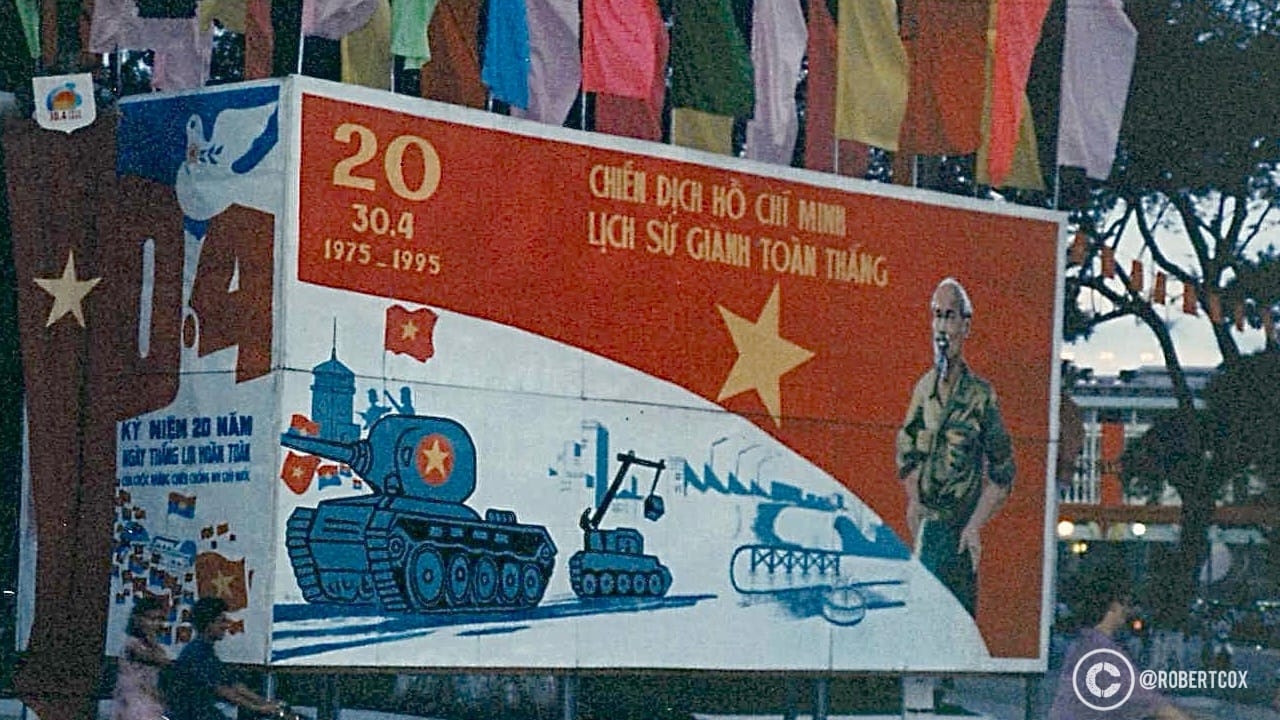 A billboard commemorating the 20th anniversary of the Fall of Saigon, which occurred on April 30, 1975. The text reads "Ho Chi Minh Campaign - History of Complete Victory” and "Celebrating 20 Years of National Reunification - Peace Restored, Prosperity Achieved."