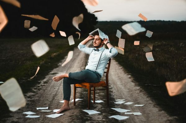 man sitting on chair with books