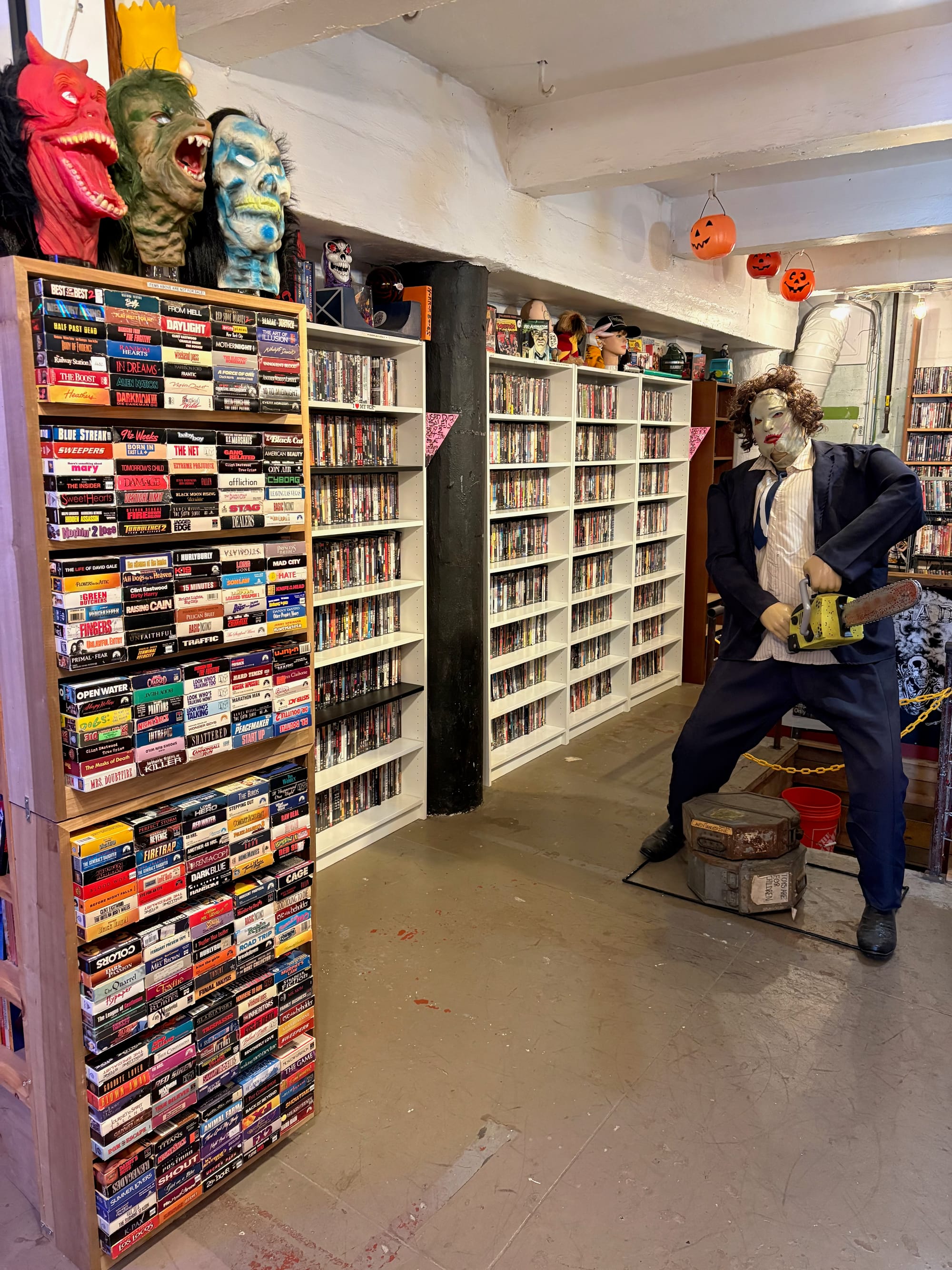 photo of the inside of The Archive store, featuring shelves full of DVDs and Blu-Rays, some Halloween masks, and a statue holding a dang chainsaw