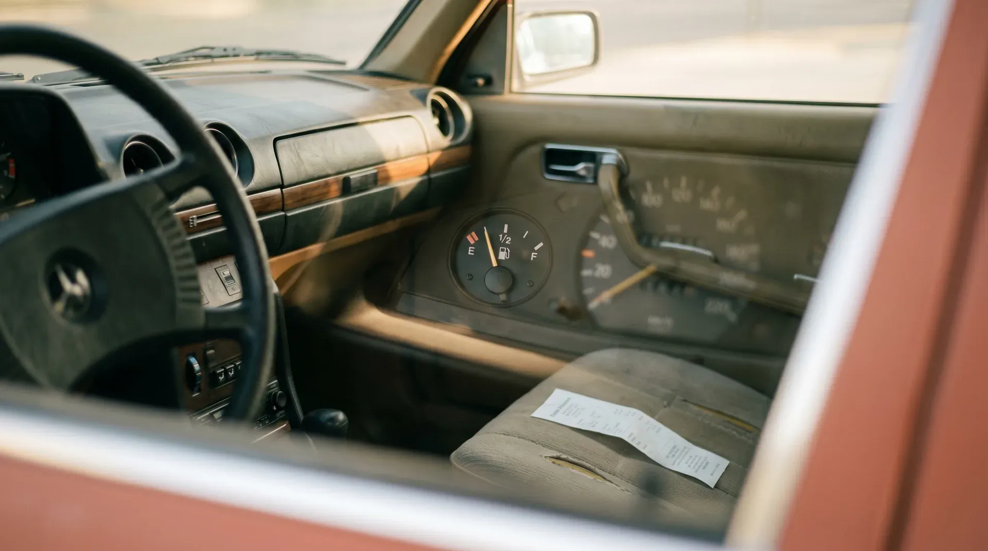 Interieur klassieke auto met stuur, dashboard en brandstofmeter, infokaart op passagiersstoel
