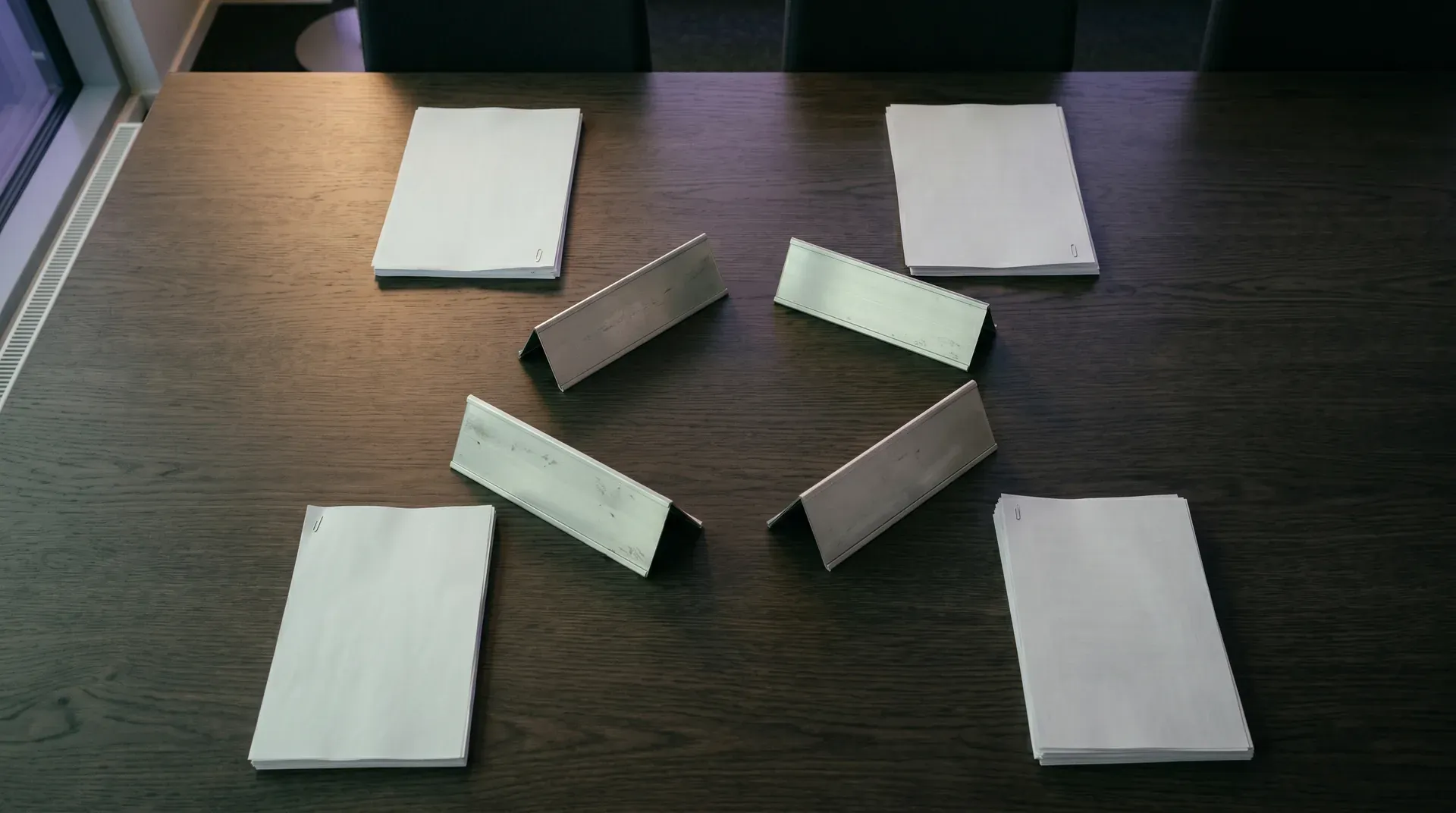 Houten tafel met witte documenten en metalen bussen, professionele bedrijfsomgeving met zachte verlichting