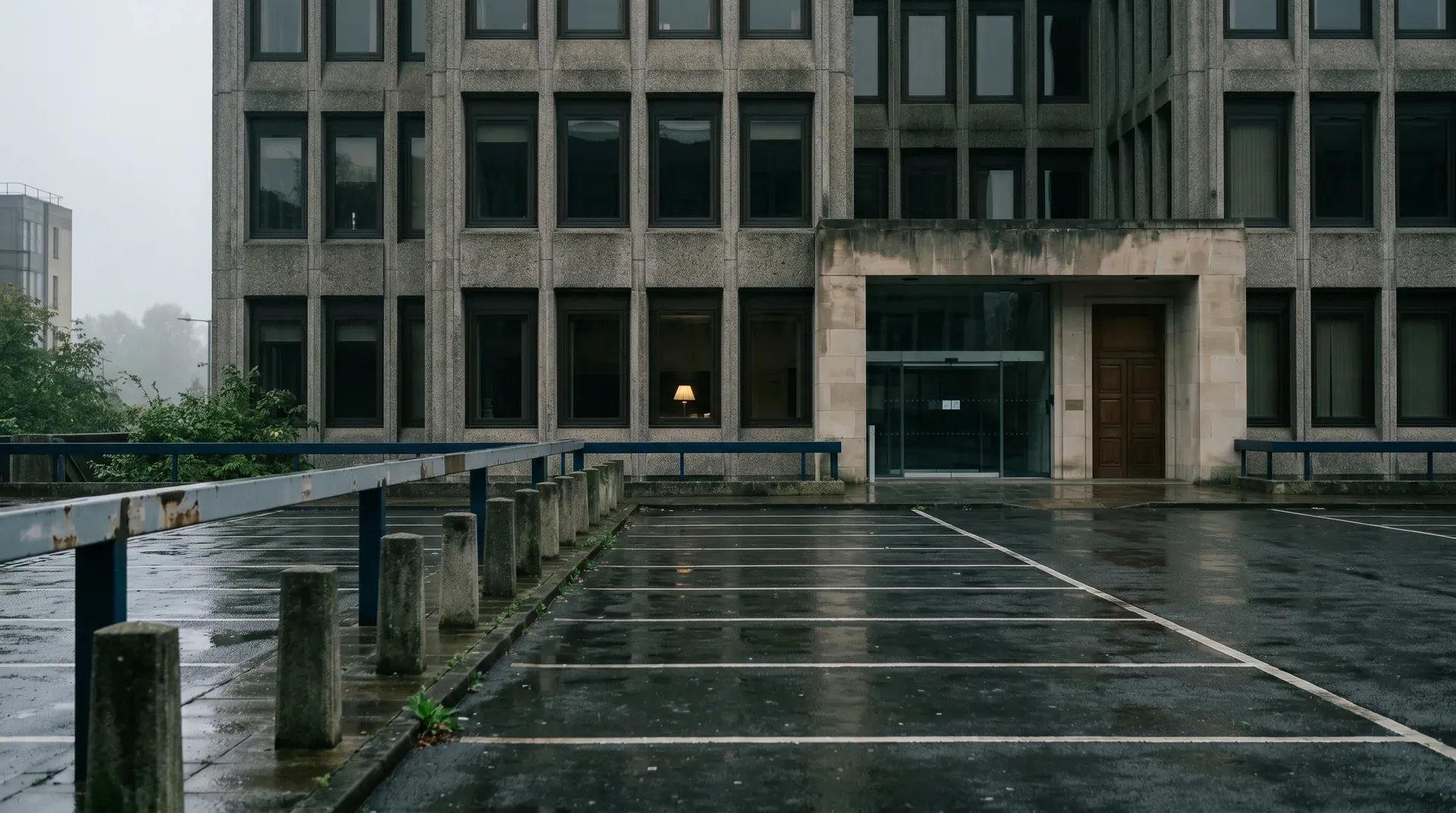 Regenachtig verlaten parkeerterrein voor modernistisch kantoorgebouw met grauwe hemel