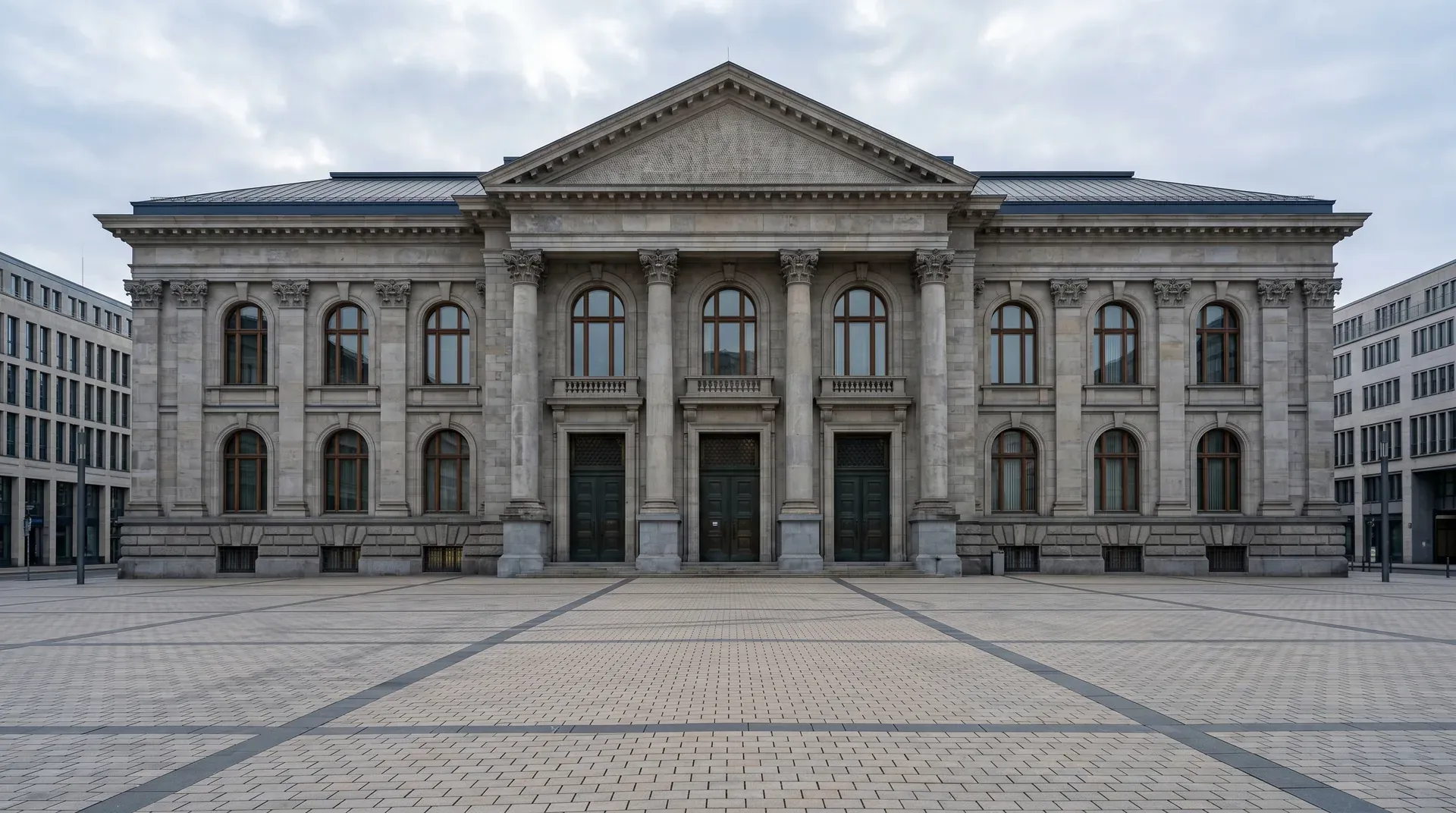 Klassiek stenen overheidsgebouw met zuilen en gevel, symmetrisch gecentreerd op groot plein.
