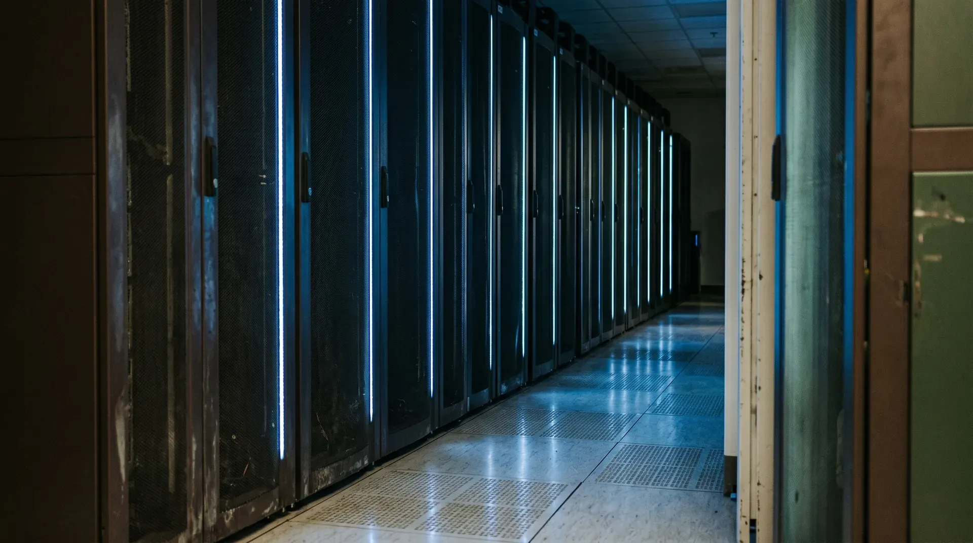 Lange gang met rijen zwarte server- of opslagkasten met blauwe verlichtingslijnen aan beide zijden