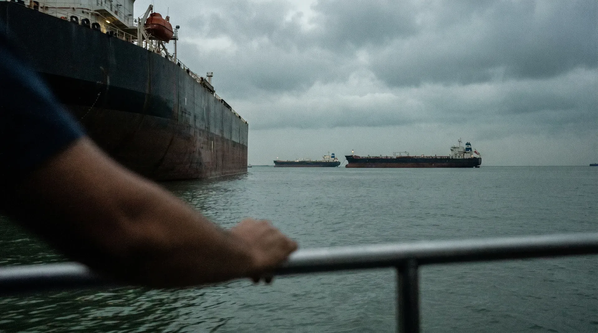 Tankerschepen op open zee gezien vanaf scheepsreling onder bewolkte hemel