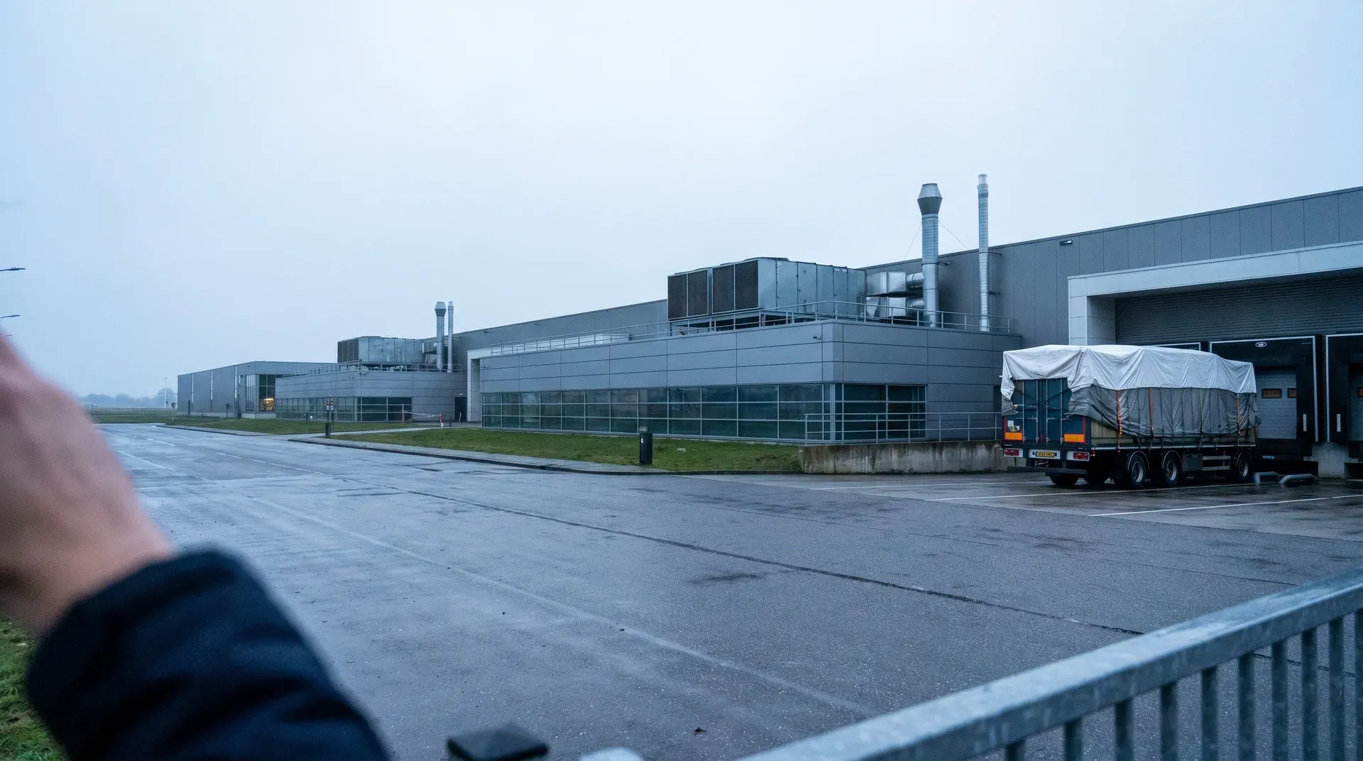 Industrieel bedrijfscomplex met vrachtwagen bij laadplatform op regenachtige dag