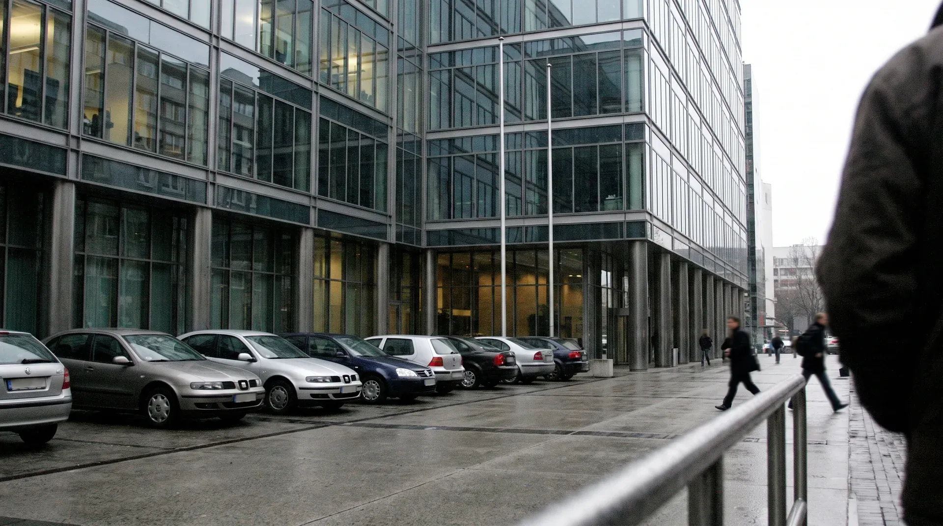 Moderne kantoorgebouw met glazen gevel, geparkeerde auto's op straat, voetgangers in zakelijk district