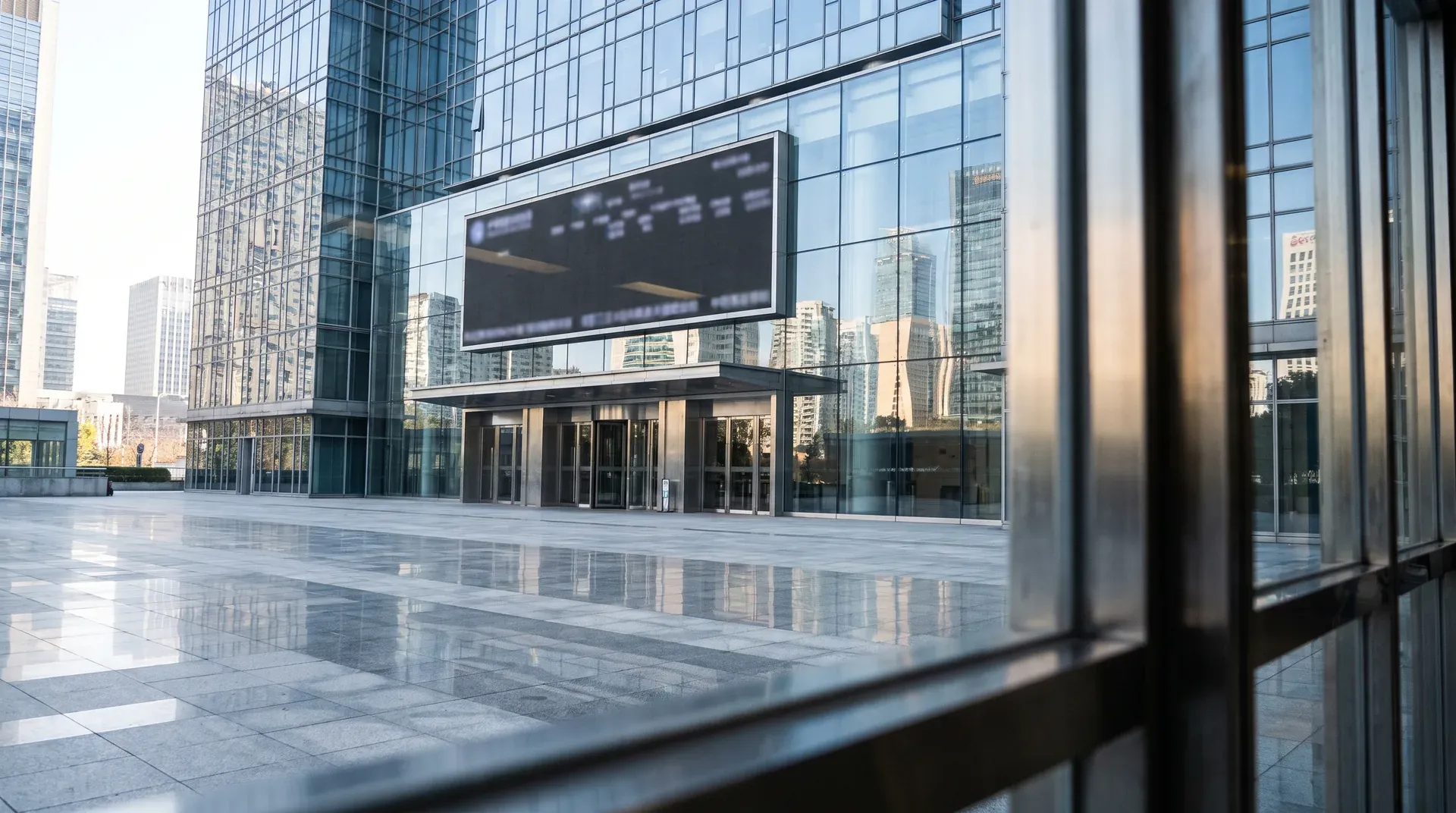 Modern glazen kantoorgebouw met digital scherm en spiegelend plaza in stedelijke skyline