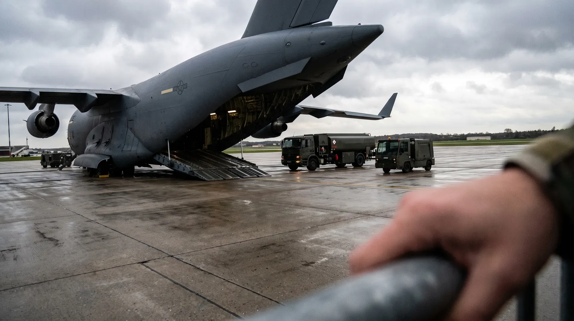 Militair vrachttoestel op landingsbaan met voertuigen en ondersteuningsmiddelen