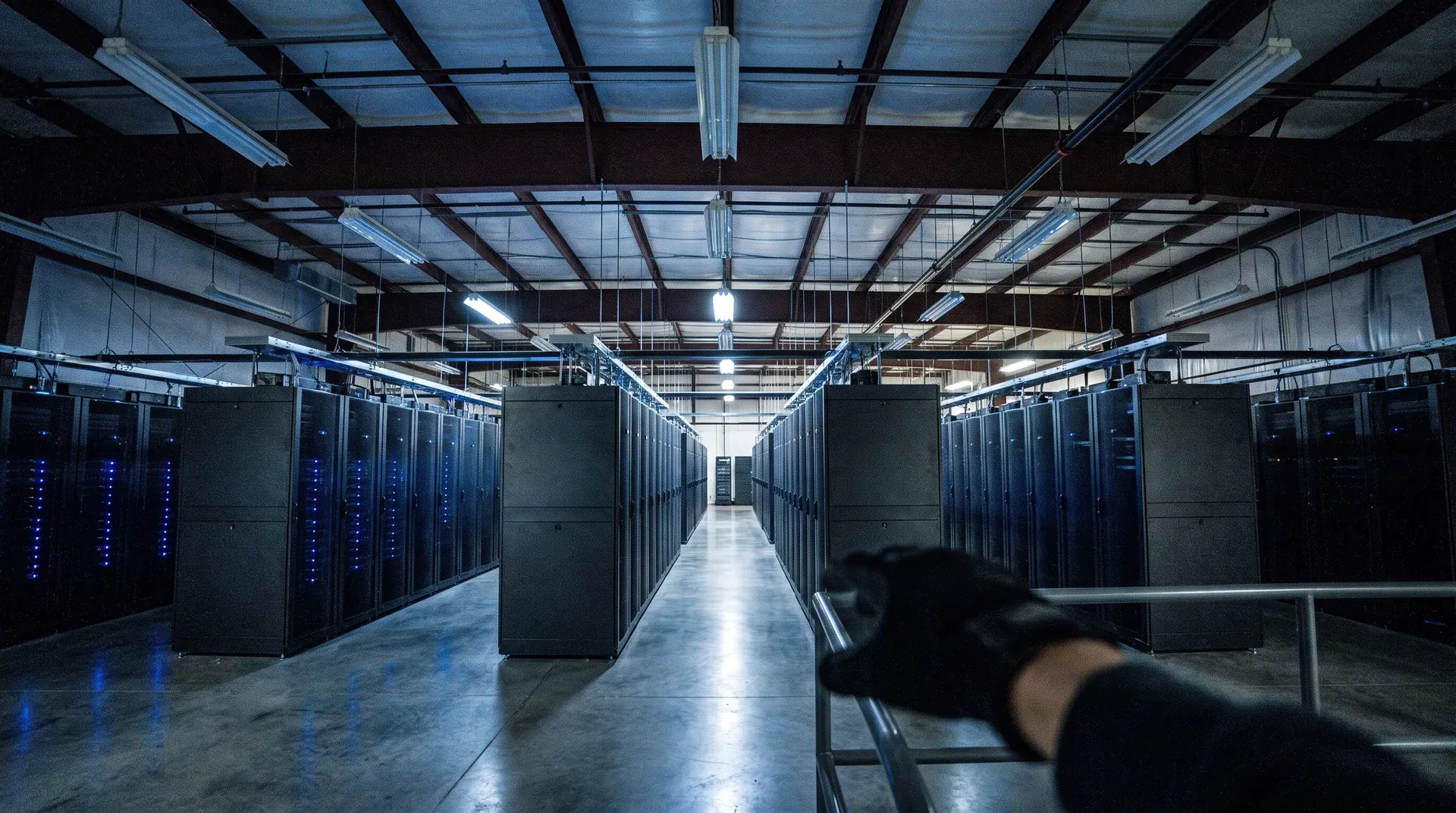 Lange rij zwarte serverkasten met blauwe ledverlichting in industriële datacenterfaciliteit