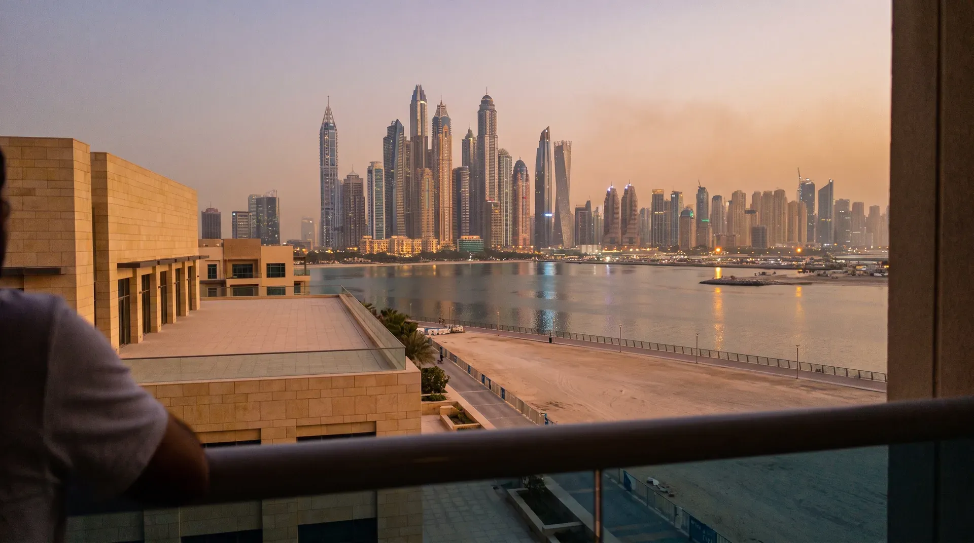 Skyline van Dubai Marina bij zonsondergang, gezien vanaf balkon met architectonisch gebouw op voorgrond