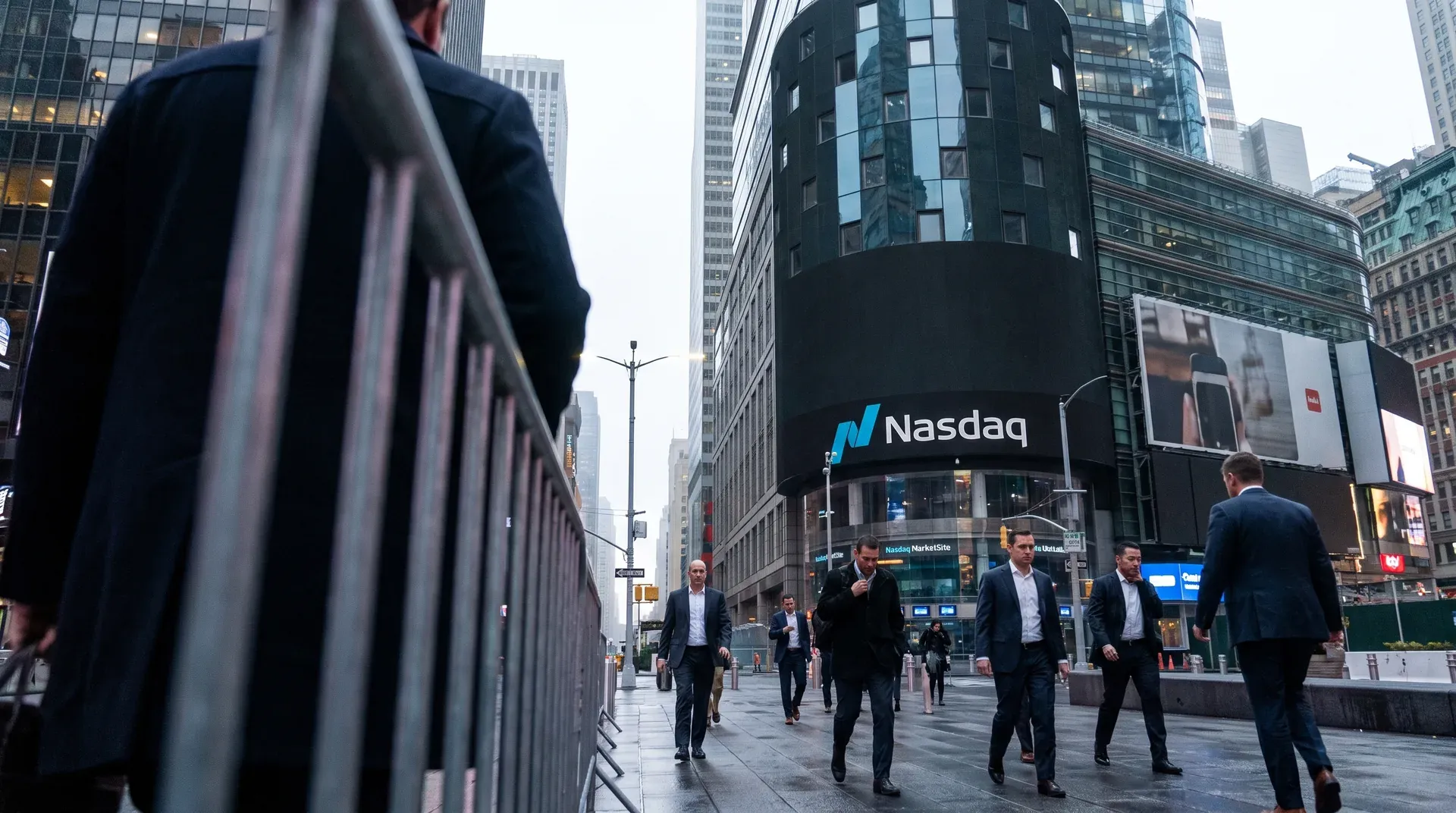 Zakenmannen in pakken lopen over straat bij Nasdaq-gebouw in Manhattan