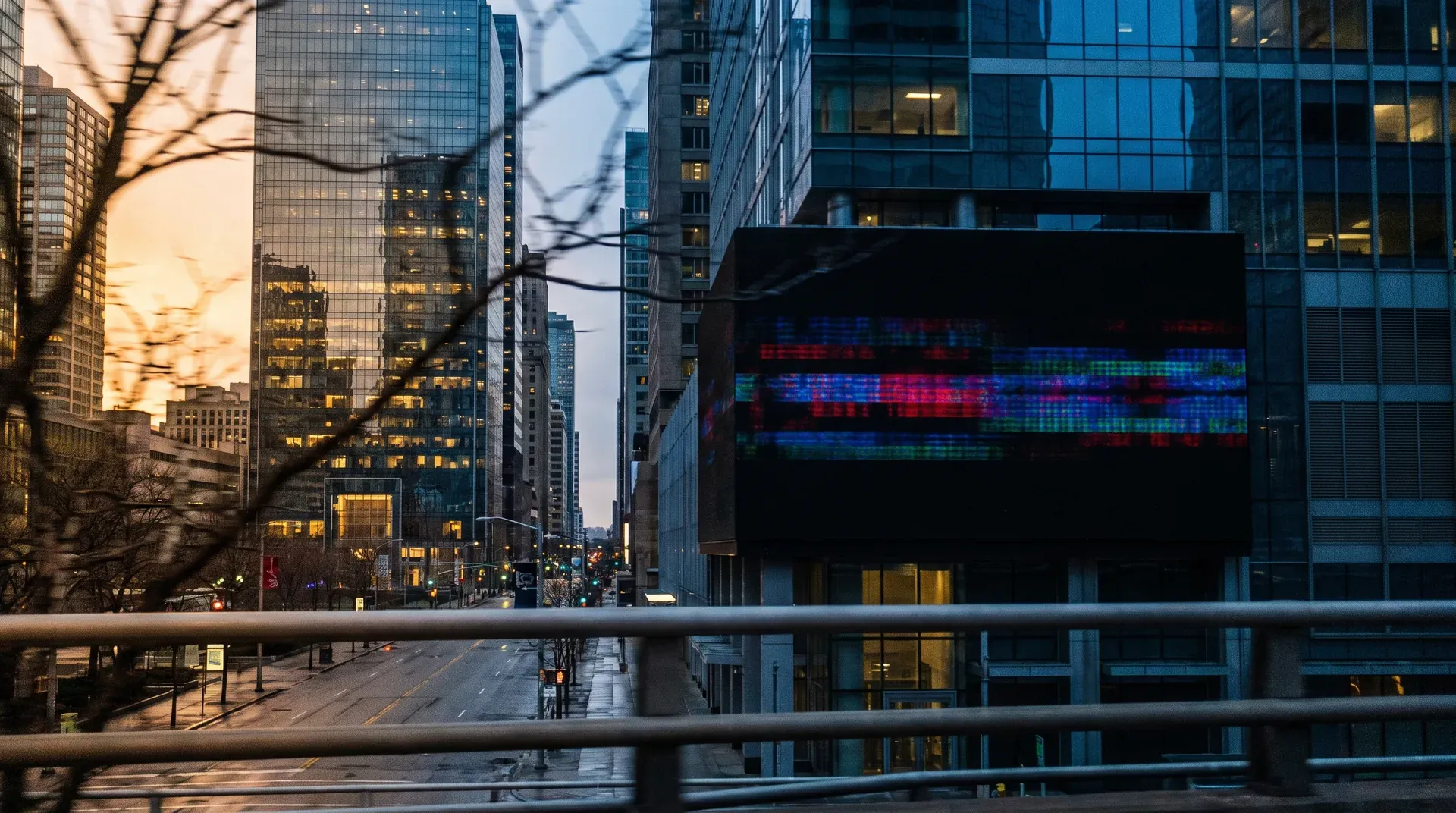 Stadsgezicht bij schemering met verlichte wolkenkrabbers, digitaal display, en natte straat.