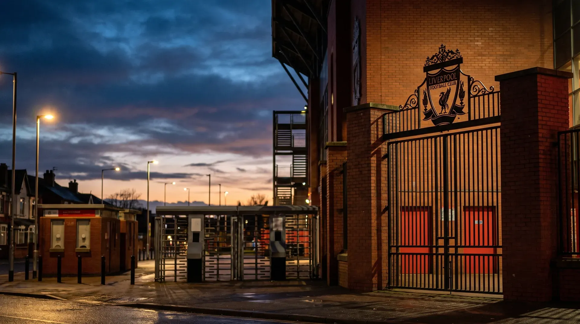 Liverpool FC stadion poort met logo bij schemering, bakstenen muur en verlichte straat.
