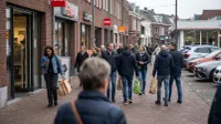 Winkelstraat met mensen die boodschappentassen dragen, HEMA en winkels zichtbaar, straatscène.