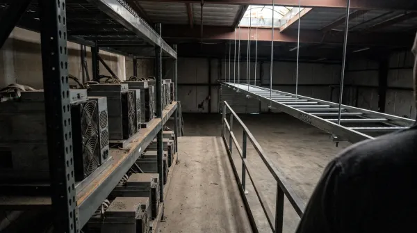 Industriële faciliteit met mining-apparatuur op planken, lege ruimte met stalen constructies en ramen.