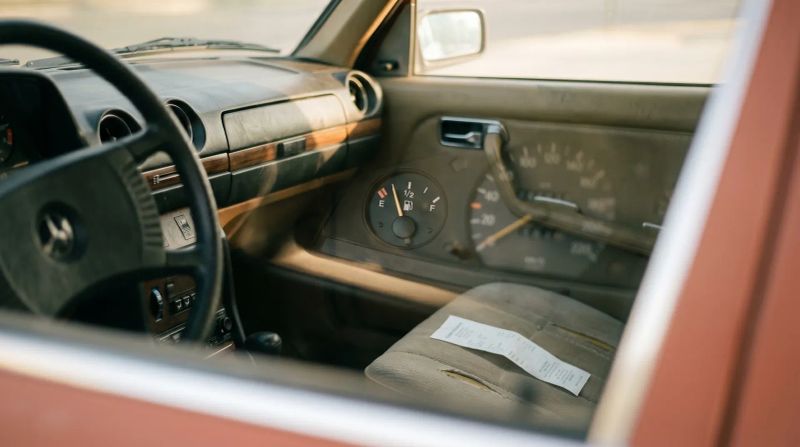 Interieur klassieke auto met stuur, dashboard en brandstofmeter, infokaart op passagiersstoel