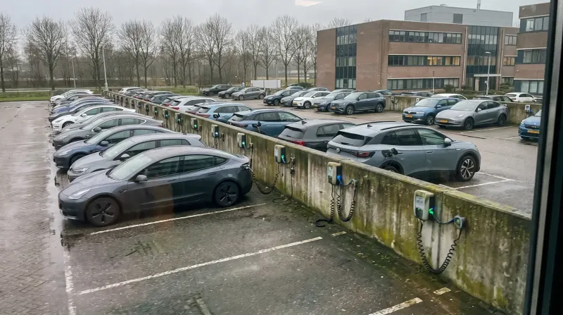 Rij elektrische auto's aan laadstations op parkeerterrein naast kantoorgebouw