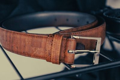 A brown leather belt with a silver buckle. The leather is slightly worn. Photo by L S on Unsplash.